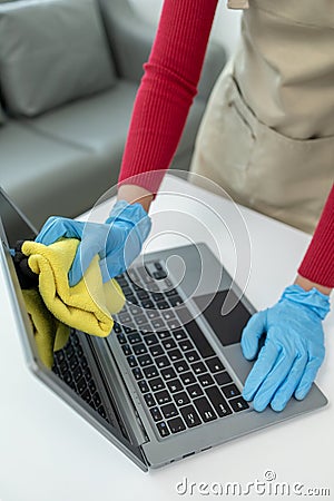Janitor cleaning the office, Clean the notebook with a rag, wear gloves and wipe with a towel, Wear rubber gloves when working Stock Photo