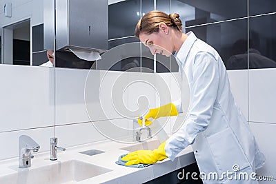 Janitor cleaning sink in public washroom Stock Photo