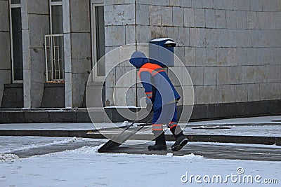 Janitor cleaning snow on the sidewalk with a shovel Editorial Stock Photo