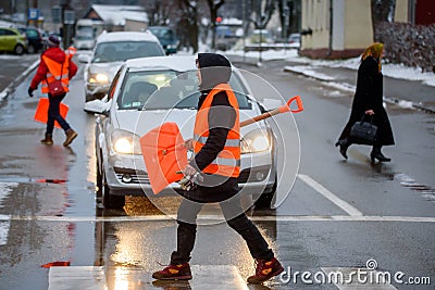 Janitor lady wearing orange vest walks with snow shovel Editorial Stock Photo