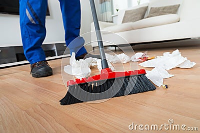 Janitor Sweeping Crumpled Papers On Floor Stock Photo