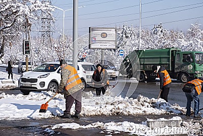 Janitors are cleaning snow on street after snowstorm. Manual work. Ice storm. Editorial Stock Photo