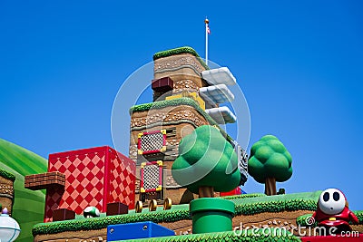 Japan - April 03, 2023: Shy guy walking on a game pixel block with green warp pipe, cloud floating and check point flag in Super Editorial Stock Photo