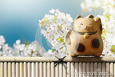 Japan Maneki Neko or Beckoning Cat standing on Bamboo Fence over Stock Photo