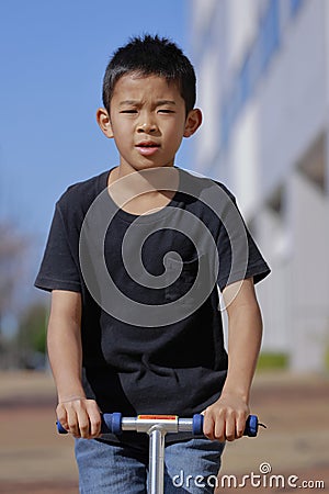 Japanese boy riding on a scooter Stock Photo