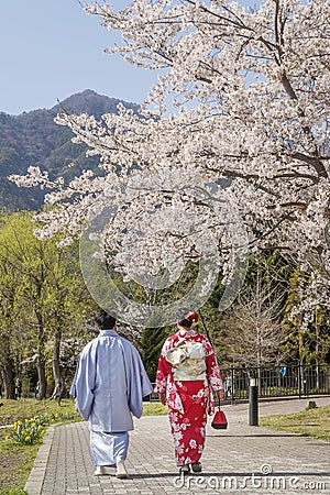 Japanese couple in traditional clothes stroll under flowering trees, Kawaguchi, Japan Editorial Stock Photo