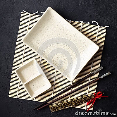 Japanese food concept. Chopsticks and empty sushi plate on bamboo mat. Stock Photo
