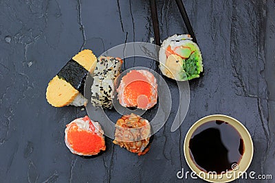Japanese food, Top view of sushi set in chopsticks on stone dark Stock Photo