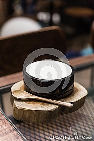 Japanese fusion dessert: White smooth milk pudding. Serve in a black ceramic bowl on timber with wooden spoon Stock Photo