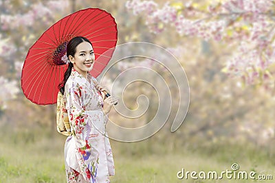 Japanese girl wearing a kimono holding a red umbrella. Beautiful Female wearing traditional japanese kimono with cherry blossom in Stock Photo