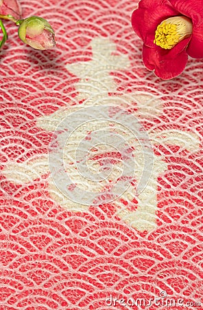 A Japanese greeting card with Tsubaki flower also called the winter rose on a traditional lace circles motif pattern Stock Photo