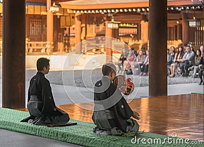 Japanese man sitting playing on a traditional tsuzumi drum in Shinto Meiji-jingu shrine Editorial Stock Photo