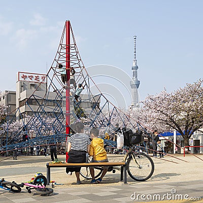 Japanese mother and son at a playground with cherry blossom and Tokyo Skytree in the background Editorial Stock Photo