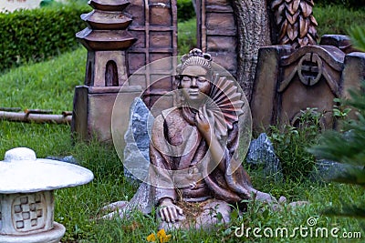 Japanese mythology concept. Front view of a traditional woman statue holding handfan in meditative posture Editorial Stock Photo