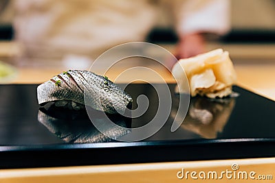 Japanese Omakase Menu: Saba Sushi Mackerel sprinkle minced Yuzu peel served by hand with pickled ginger on glossy black plate. Stock Photo