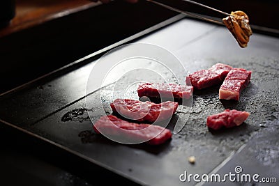 Japanese premium beef sliced with juicy marbled line grilling on black barbecue plate while hand pick mussel seafood by chopsticks Stock Photo