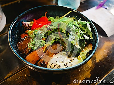 Japanese ramen with spoiled egg and fried pork and vegetables bowl inside restaurant Stock Photo