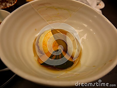 Japanese ryokan kaiseki dinner warm dish including sweet shrimp dumpling, pumpkin, yam and butterbur in white ceramic bowl Stock Photo