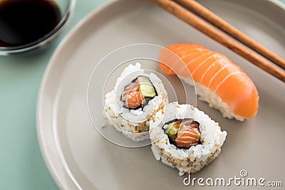 Japanese salmon Nigiri and inside out California Sushi with avocado, soy sauce and wooden chopsticks on porcelain plate Stock Photo