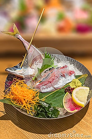 Japanese seafood sashimi cuisine of Ayu raw fish pierced on a skewer served in a metal plate. Stock Photo