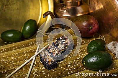 Volcano sushi roll with black rice and unagi eel served with sesame seeds with copper tableware on wooden background. Still life Stock Photo