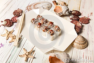 Japanese Volcano Sushi Roll on delivery box with chopsticks. Asian dish with raw salmon, flying fish roe Tobiko served with Unag Stock Photo