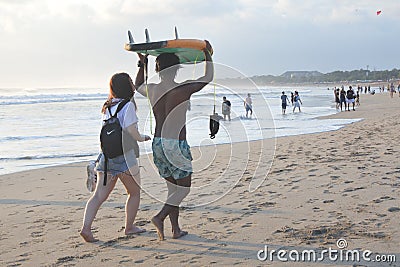 Japanese woman and Balinese male gigolo walking on Kuta beach in Bali Indonesia Editorial Stock Photo