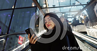 Japanese, woman on escalator and smartphone, travel and commute, communication with social media and adventure. Text Stock Photo