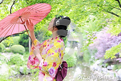 Traditional Asian Japanese beautiful Geisha woman wears kimono bride with a red umbrella in a graden Stock Photo