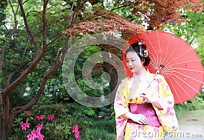 Traditional Asian Japanese beautiful Geisha woman wears kimono hold a umbrella on hand in a summer nature Stock Photo