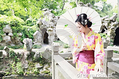 Traditional Asian Japanese beautiful woman bride wears kimono with white umbrella stand by bamboo in outdoor spring garden Stock Photo
