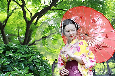 Traditional Asian Japanese woman in a garden hold a red umbrella Stock Photo