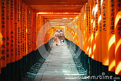 Japanese woman in kimono dress among red wooden Tori Gate at Fushimi Inari Shrine in Kyoto, Japan Editorial Stock Photo