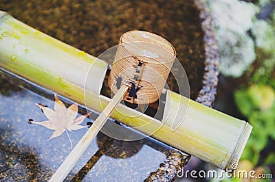 Japanese wooden purification dipper in a chozubachi or water basin used to rinse the hands in Japanese temples Stock Photo