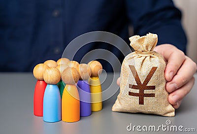 A businessman holds a japanese yen money bag near a group of people figurines. Stock Photo