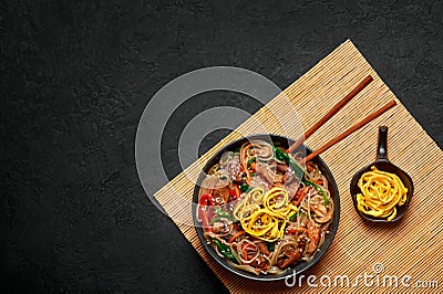Japchae in black bowl on dark slate table top. Korean cuisine glass chapchae noodles dish with vegetables and meat Stock Photo