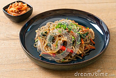 Japchae or stir-fried Korean vermicelli noodles with vegetables and pork topped with white sesame Stock Photo