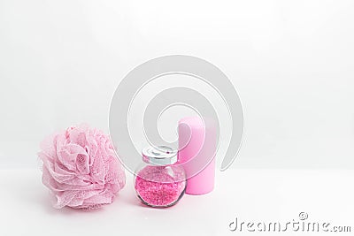 A Jar of bath salt, a sponge for bath and a candle are stand nearby. Light pink objects on a white background. The Stock Photo