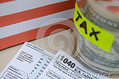 Jar with coins and dollar inside with mark tax on it, 1040 form and usa flag Editorial Stock Photo