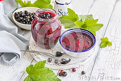 Jar of homemade fresh currant jam with shugar. Fresh berries black currant on white wooden background Stock Photo