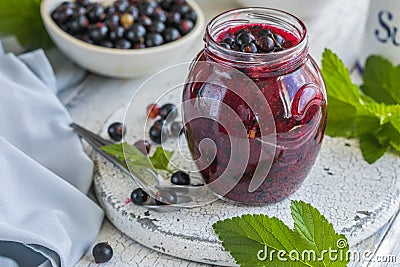 Jar of homemade fresh currant jam with shugar. Fresh berries black currant on white wooden background Stock Photo