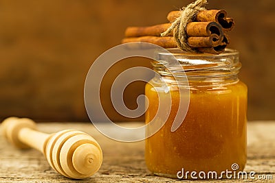 Jar of honey with drizzler and cinnamon on wooden background Stock Photo