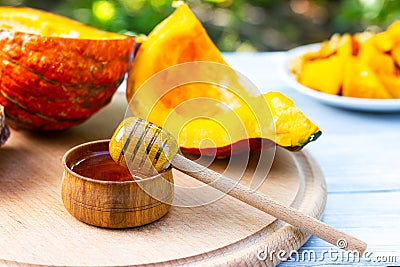 A jar of honey with a wooden spoon and pieces of pumpkin. Daylight Stock Photo