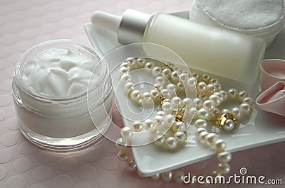 A jar of luxury beauty face cream and serum bottle with pearls on pink color background with copy space. Stock Photo
