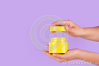 Jar of moisturizing facial cream. Yellow plastic container with cream vitamin c on purple background. Yellow unbranded, balsam, Stock Photo