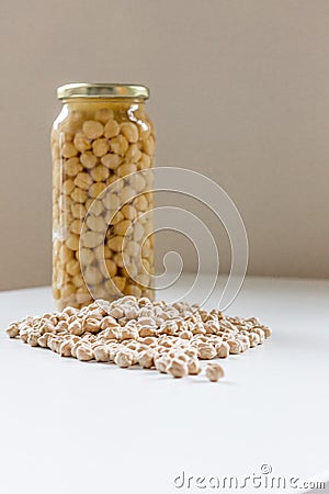 Jar of non-perishable cooked chick peas with dried chick peas spilled in front of it Stock Photo