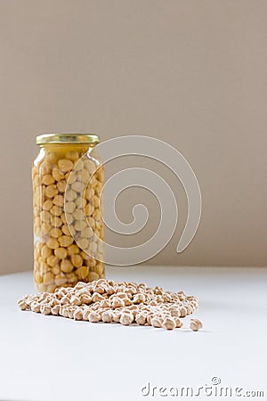 Jar of non-perishable cooked chick peas with dried chick peas spilled in front of it Stock Photo