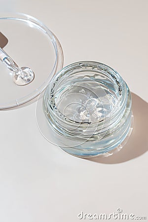 Jar with transparent cosmetic product, aloe gel or cream gel on beige pastel background. Liquid gel spilled out of Stock Photo