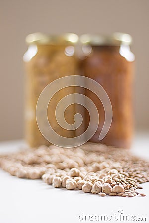 Jars of non-perishable chickpeas and lentils with spilled seeds on the table purchased Stock Photo