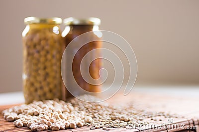Jars of non-perishable chickpeas and lentils with spilled seeds on the table Stock Photo